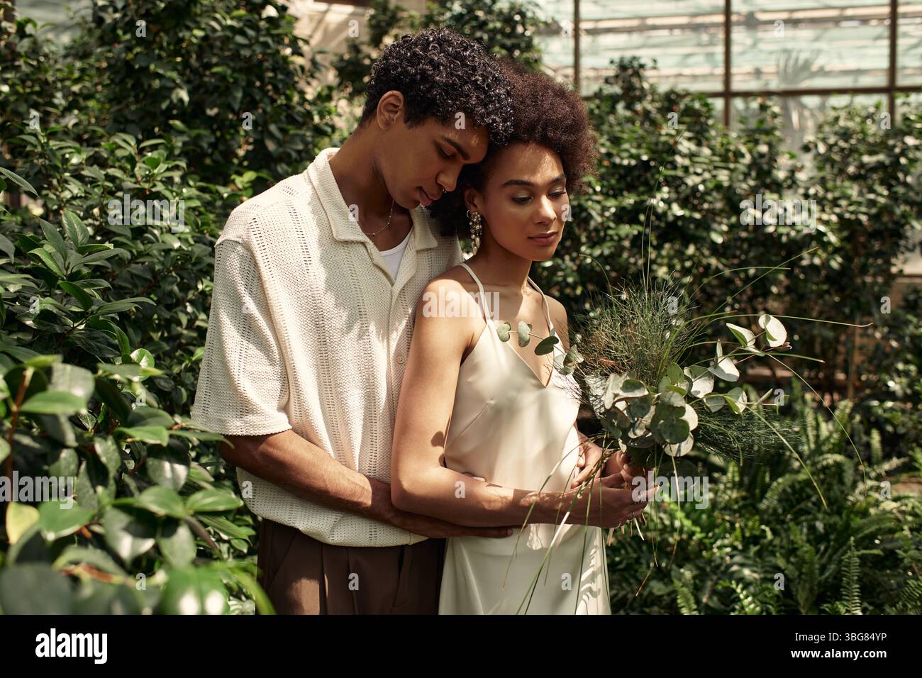Stand Close A loving couple stands close together amidst a thriving greenhouse ...