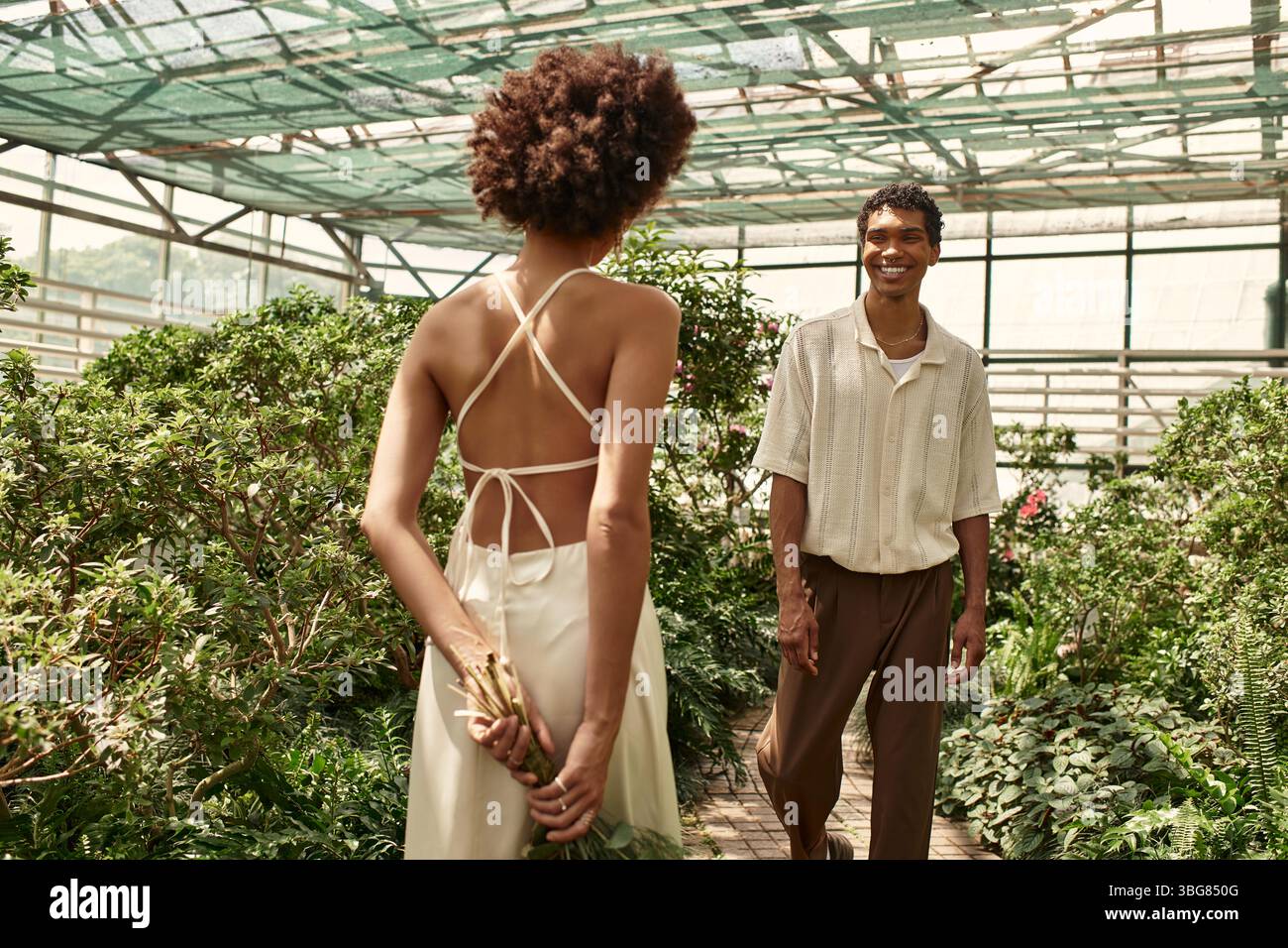 In a vibrant greenhouse, a young couple shares their love among lush plants. Stock Photo