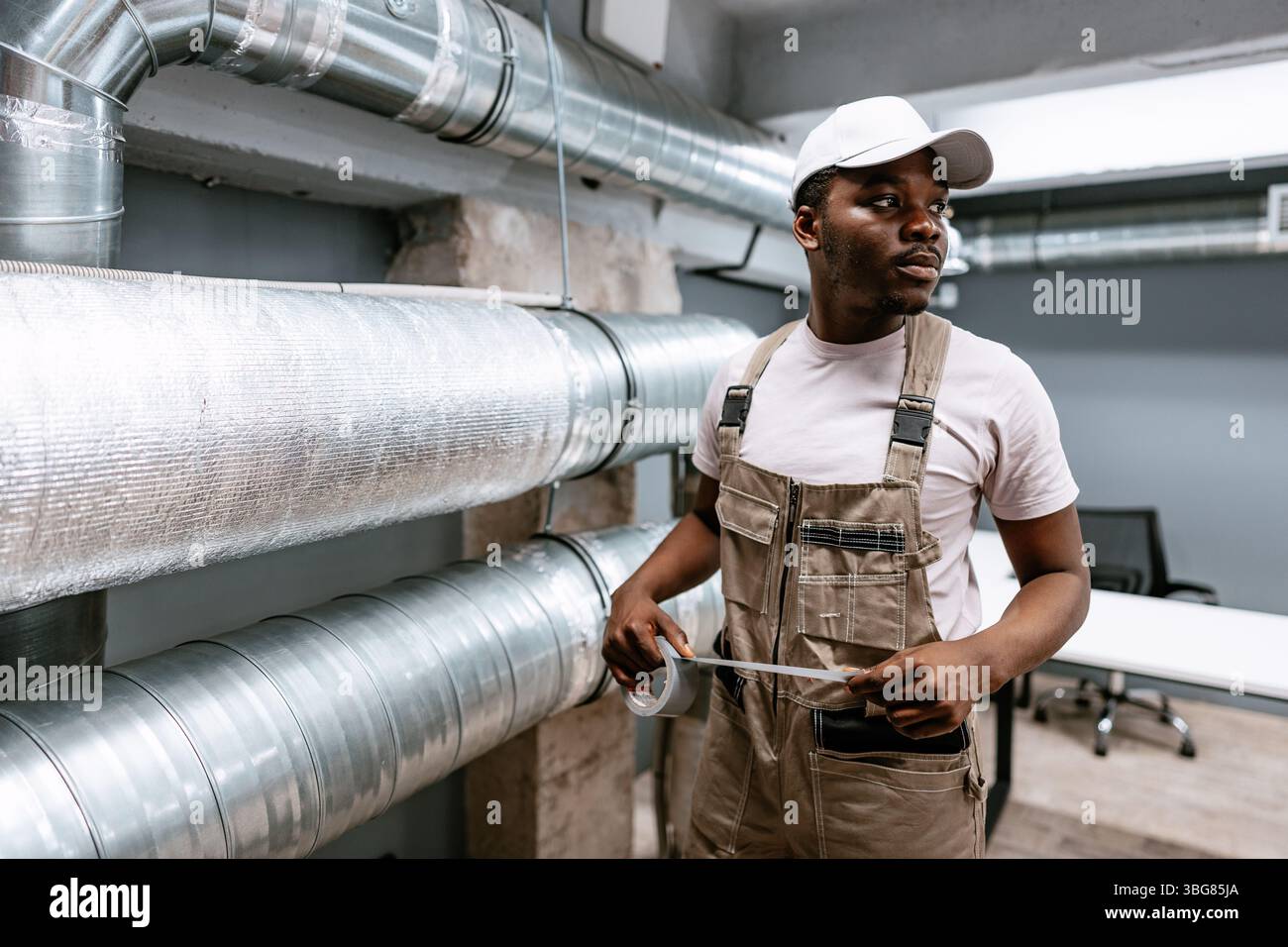 Professional worker performs maintenance on ventilation systems in a modern office setting during the day Stock Photo