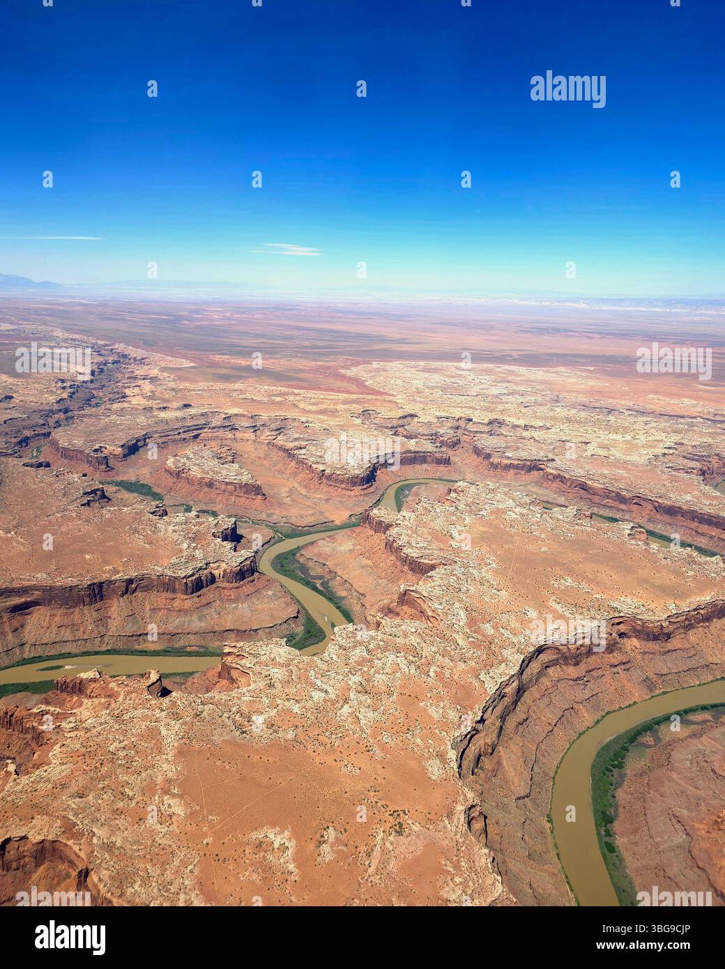 Aerial view of a winding green river cutting through vast red rock canyons in Utah. - Smartphone Captured Stock Image
