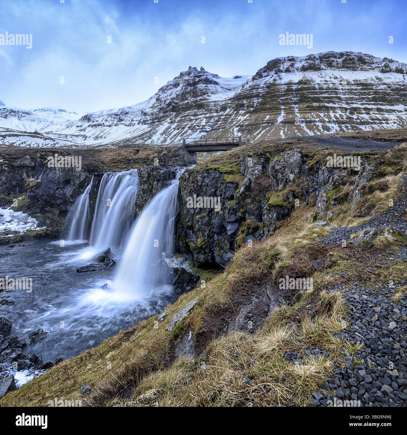 Beruehmter Wasserfall Kirkjufellsfoss unter dem kegelfoermigen Berg Kirkjufells Stock Photo
