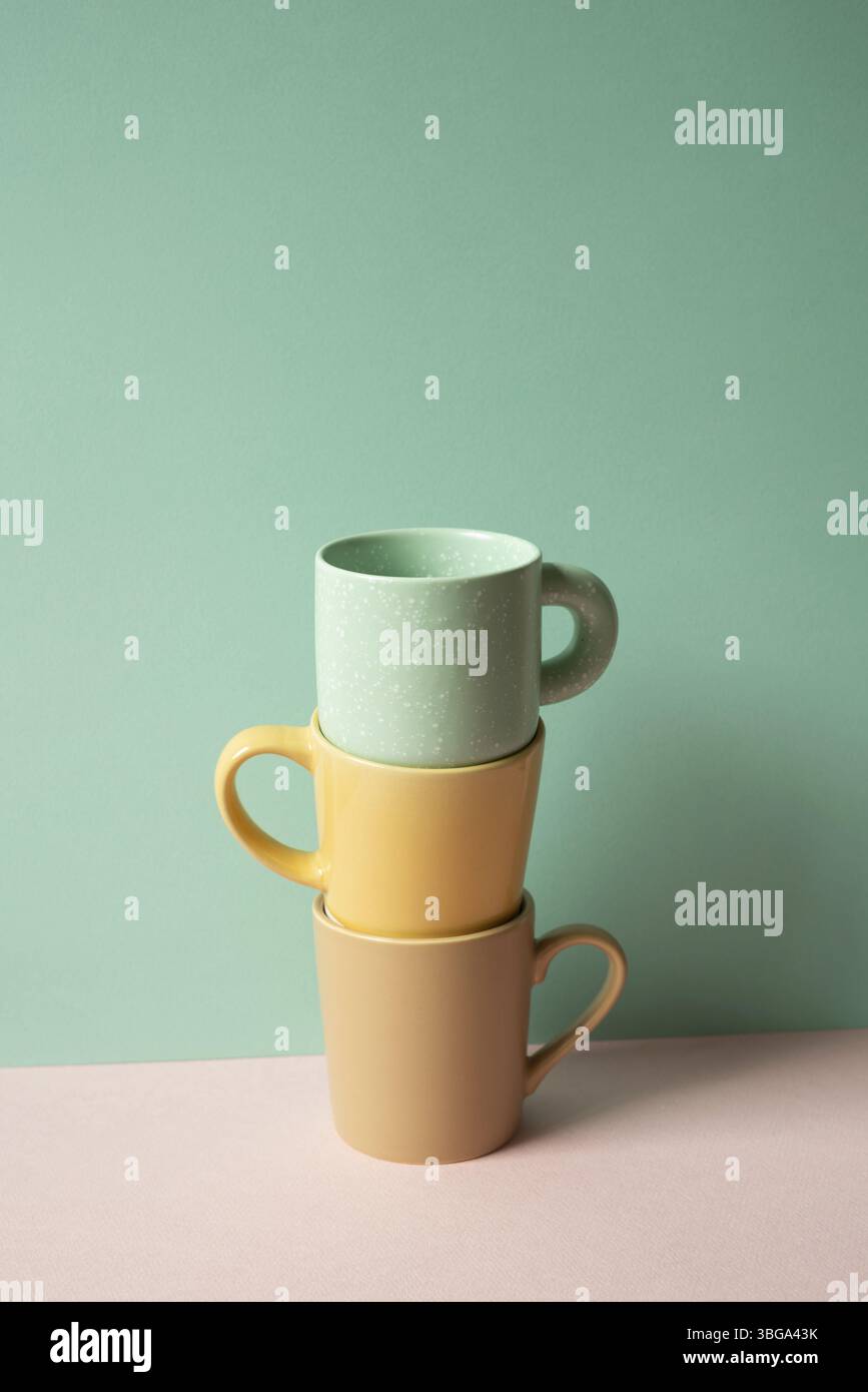 Stack of mug cup on pink table. mint green wall background Stock Photo