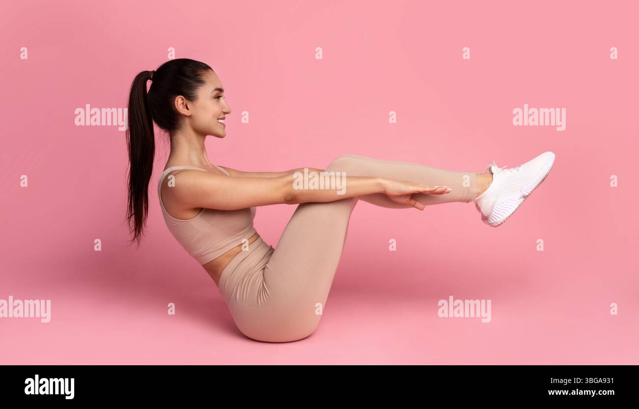Smiling Young Woman Doing Abs Exercise With Leg Raise Stock Photo