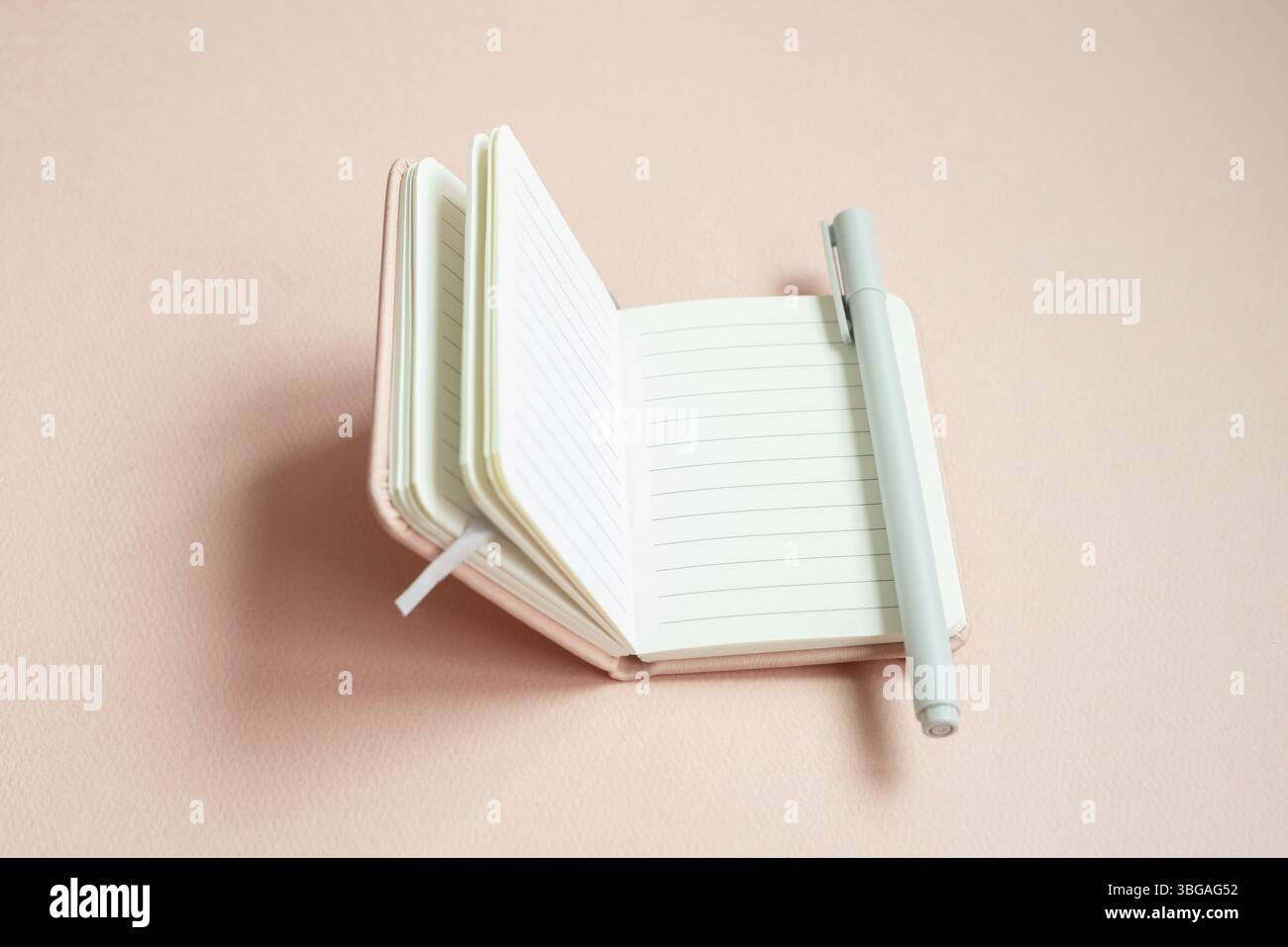 Open lined notebook and pen on pink desk background Stock Photo