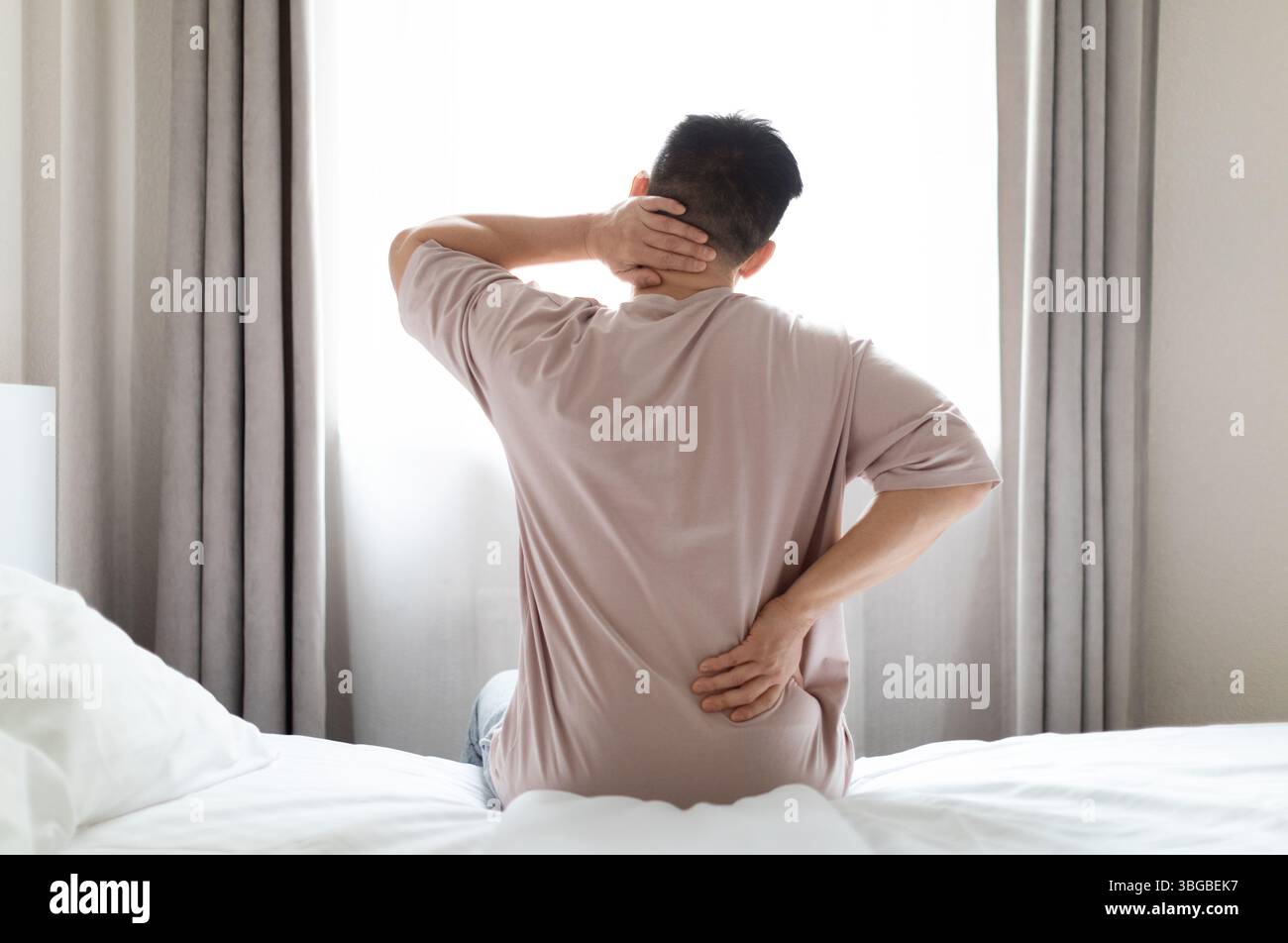 Tired man suffering from back pain at home in bedroom Stock Photo - Alamy