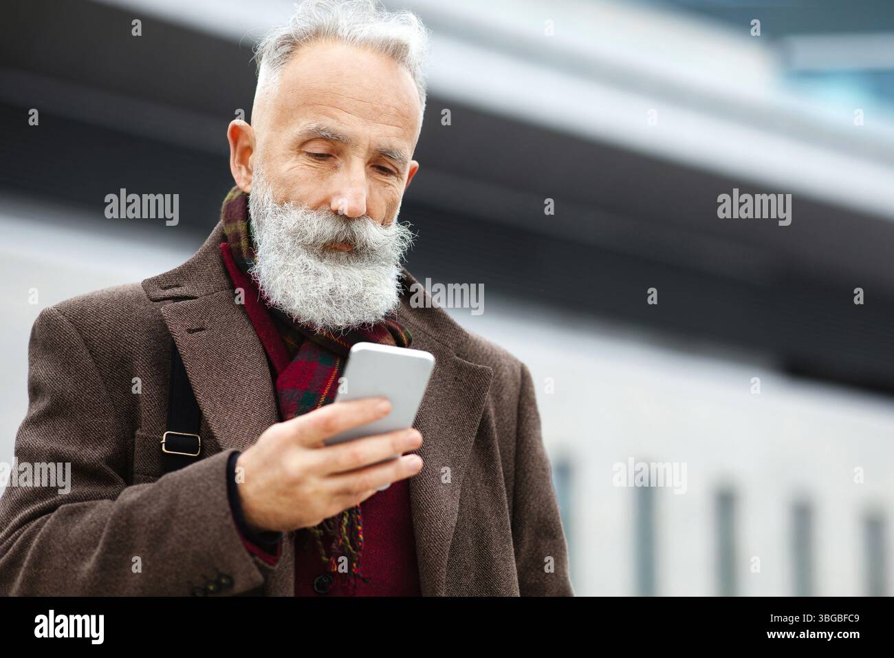 Grey-haired businessman using smartphone on the street Stock Photo