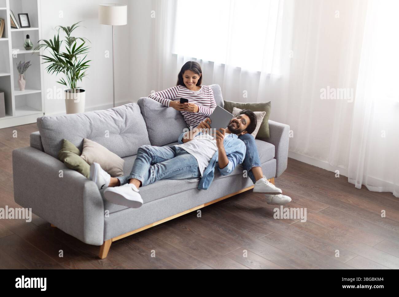 High angle view relaxed eastern lovers using gadgets at home Stock Photo