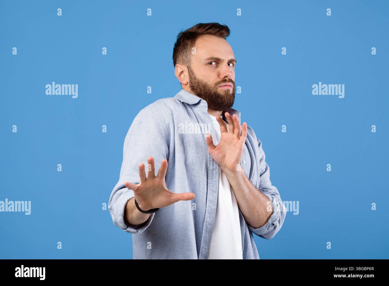 Repulsed millennial guy rejecting something, making STOP gesture over blue studio background Stock Photo