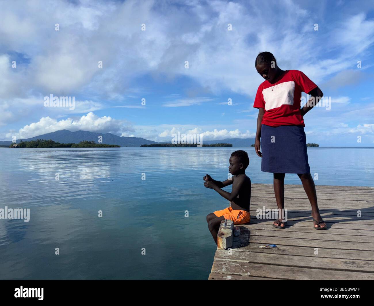 Young woman and boy fishing from jetty, Munda, New Georgia, Roviana Lagoon, Western Province, Solomon Islands. No PR Stock Photo