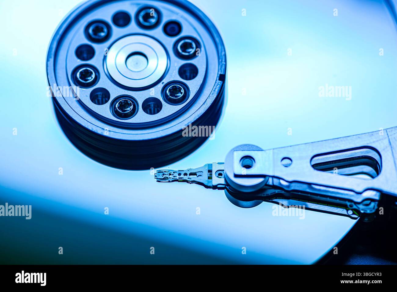 Hard disk drive reading data with blue light reflecting on the platter surface Stock Photo