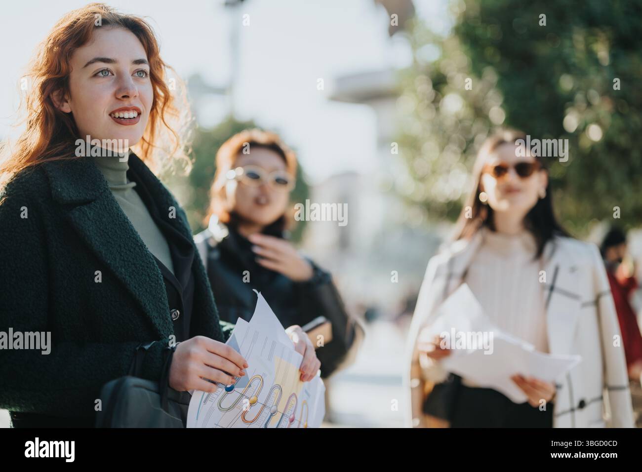 Three businesswomen collaborating outdoors on a project with documents and strategy Stock Photo