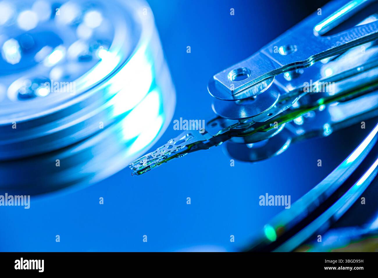 Milan, Italy 1 January 2025: Hard disk drive reading data with its head is reflecting blue light, concept of data storage and technology Stock Photo