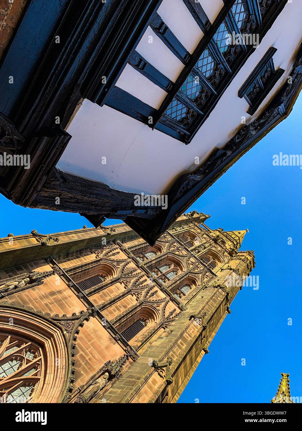 Old Coventry Cathedral and a timber framed Tudor building against a clear blue sky - Smartphone Captured Stock Image