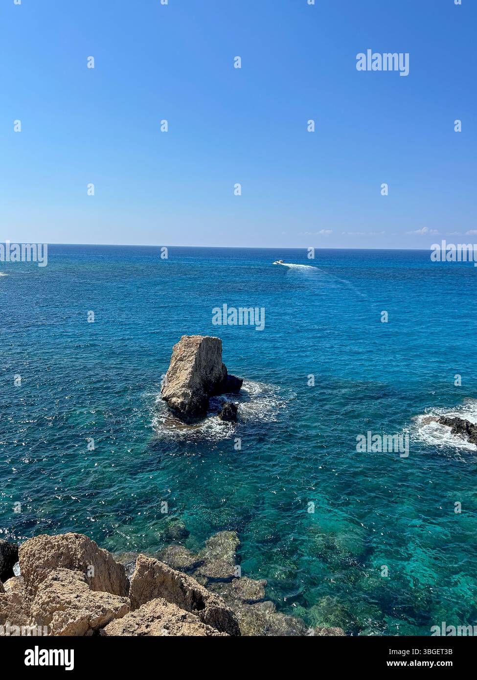 Clear turquoise water surrounds rugged rocks under a bright blue sky. A peaceful seascape ideal for vacation, travel, and nature concepts. - Smartphone Captured Stock Image Clear turquoise water surrounds rugged rocks under a bright blue sky. A peaceful seascape ideal for vacation, travel, and nature concepts. - Smartphone Captured Stock Image