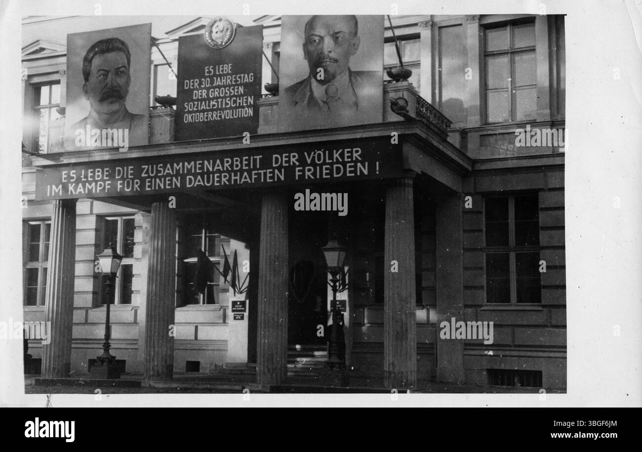Zum 30. Jahrestag der Großen Sozialistischen Oktoberrevolution wurde das Haus der Kultur der Sowjetunion Unter den Linden in Berlin festlich geschmückt. Auf dem Gebäude sind große Porträts von Stalin und Lenin sowie Losungen zur internationalen Zusammenarbeit und zum Frieden angebracht. Stock Photo