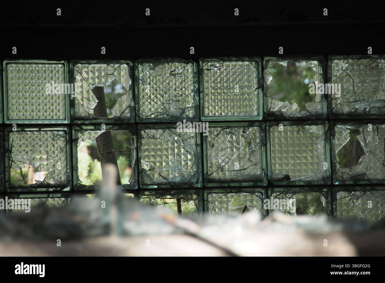 Broken Glass Block Window with Cracks and Missing Shards Stock Photo