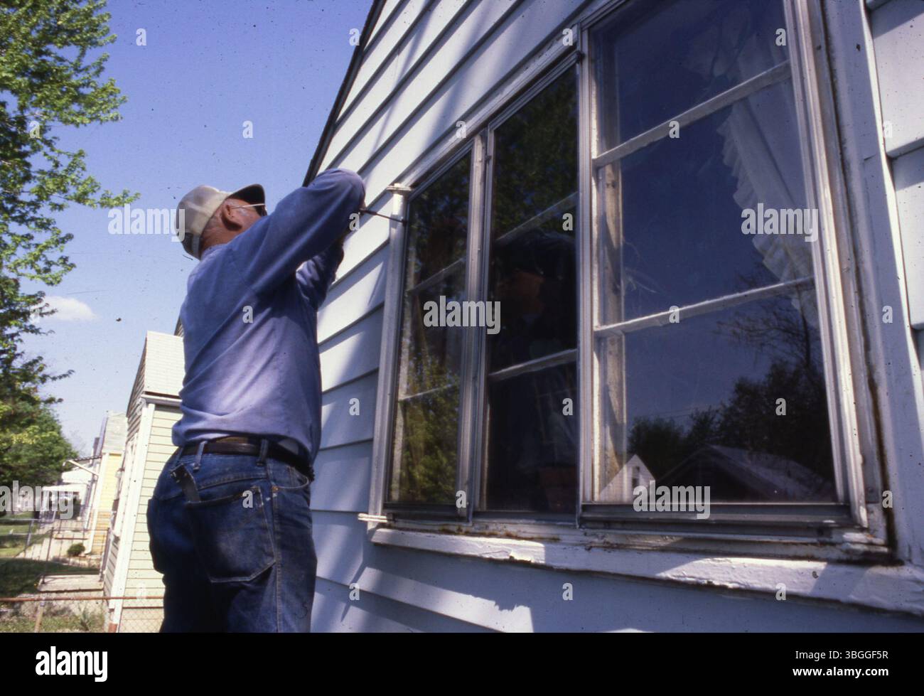 A worker performs maintenance on an exterior home window in 1980 ...