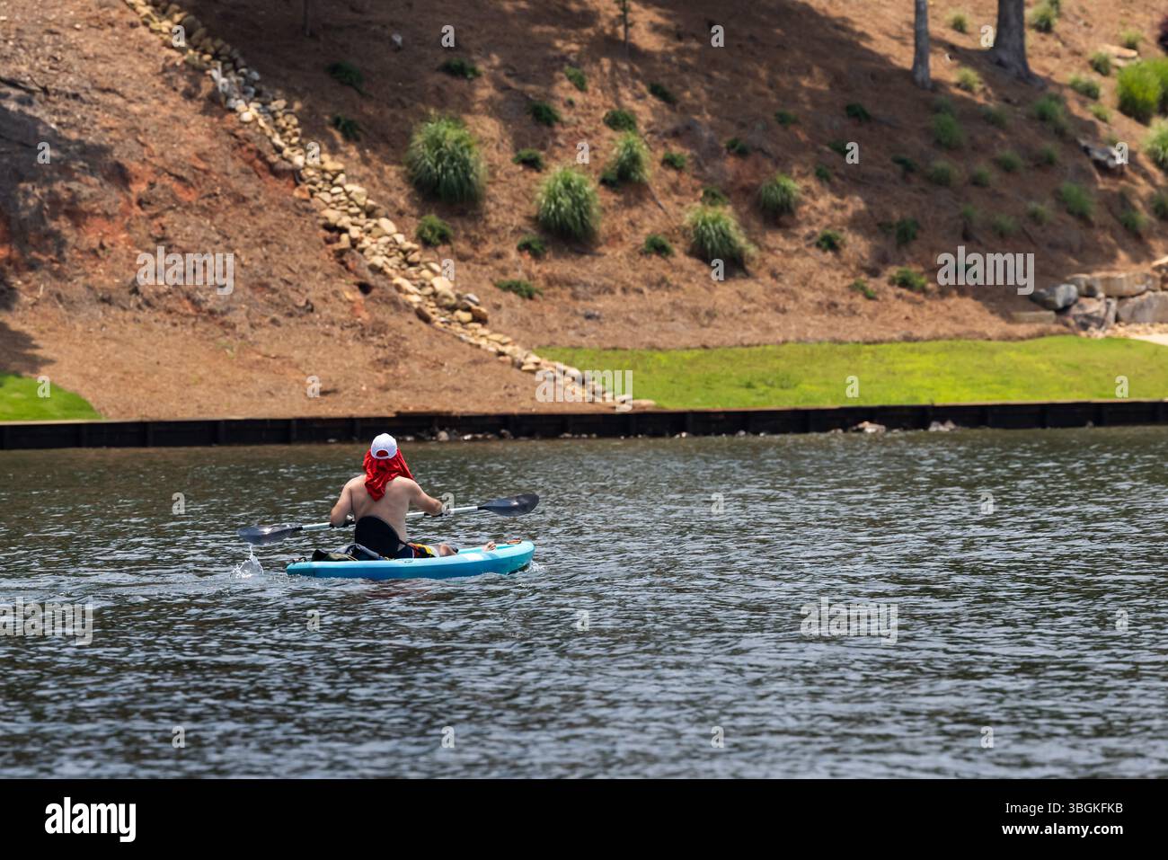 Adult man paddling kayak enjoying summer day on lake. Stock Photo