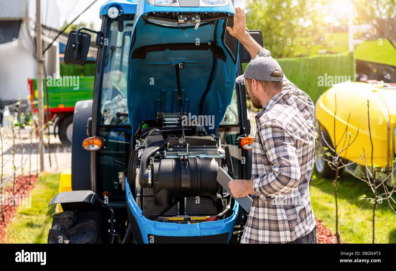 Tractor Engineer Male technician diagnosing tractor engine at farm Stock Photo - Alamy