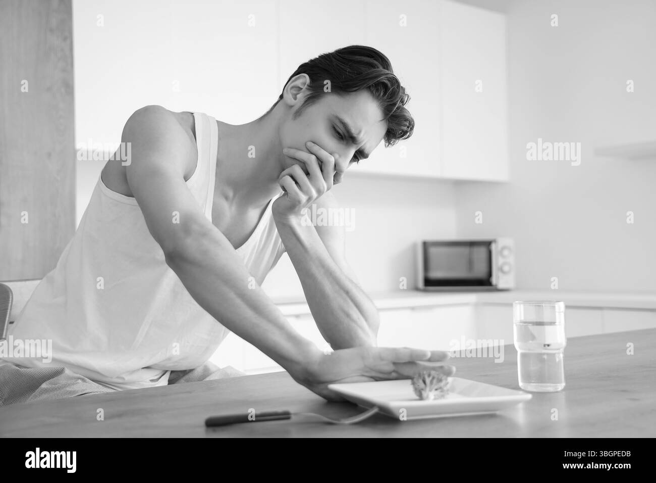Young man with anorexia refusing from food in kitchen Stock Photo
