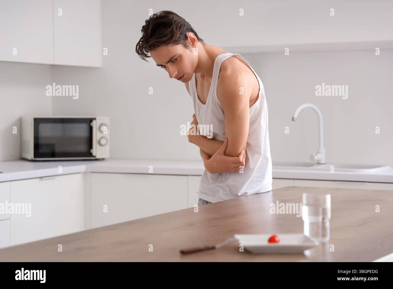 Young man with anorexia refusing from food in kitchen Stock Photo