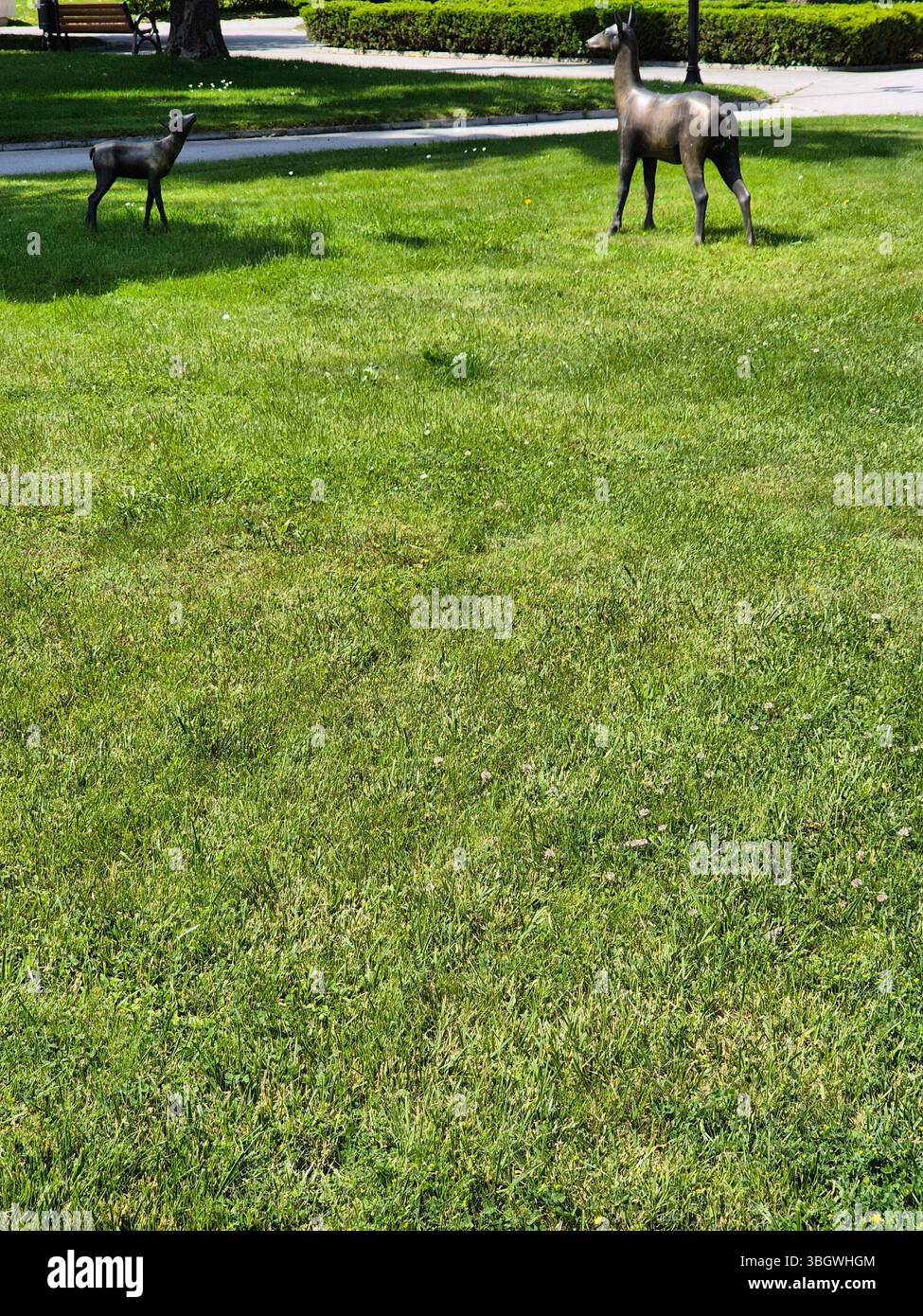 Garden sculptures of deer on a green lawn. springtime - Smartphone Captured Stock Image