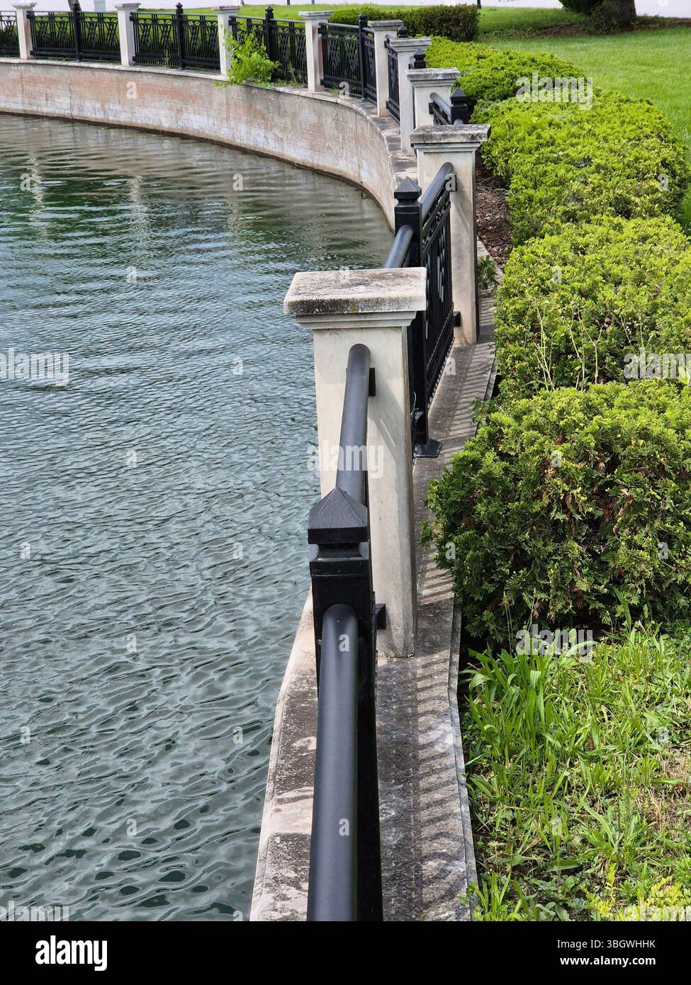 Pond with stone parapet and green bushes. - Smartphone Captured Stock Image