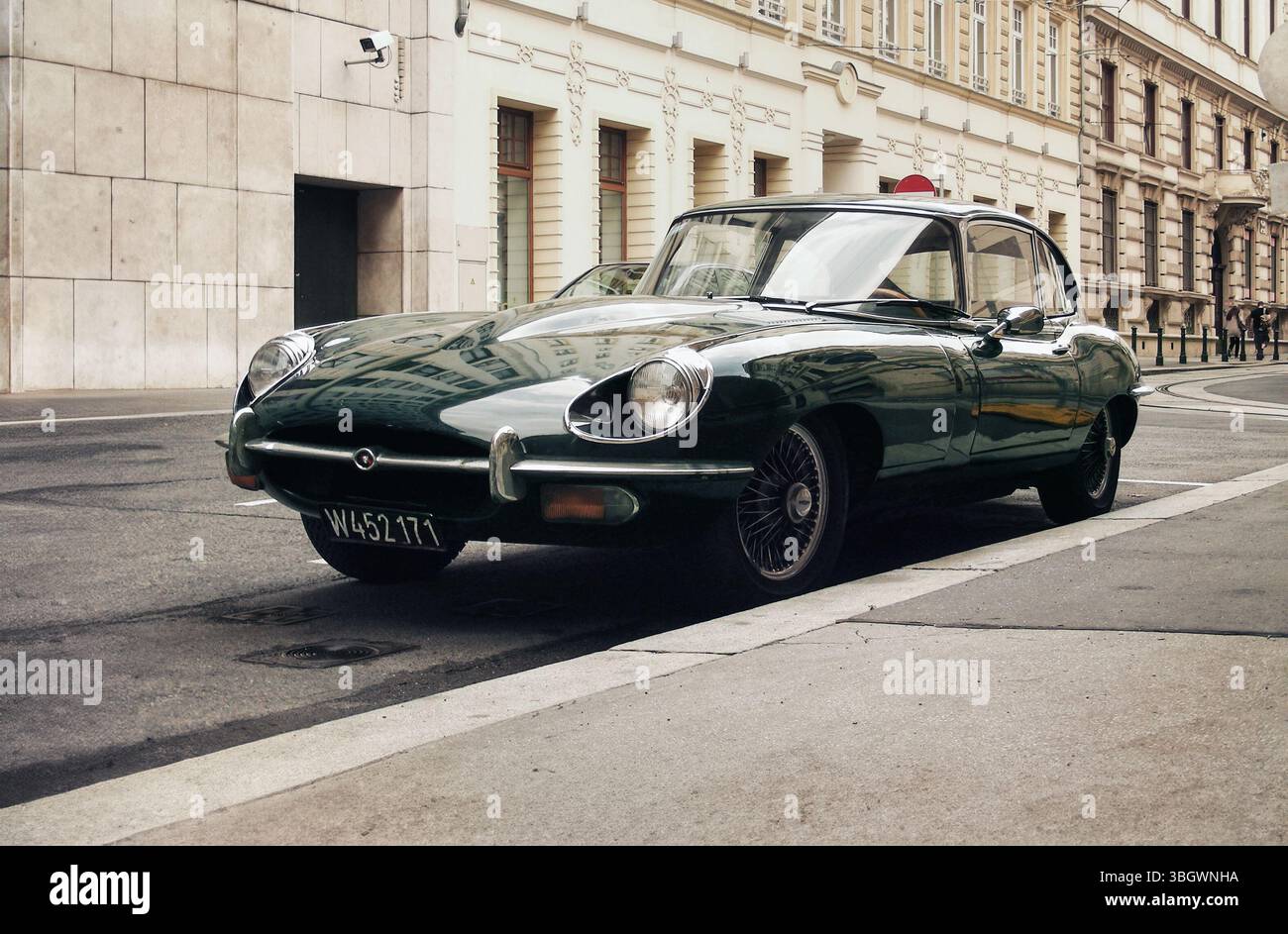 green Jaguar E-type on a street in old town. Three quarter front view ...
