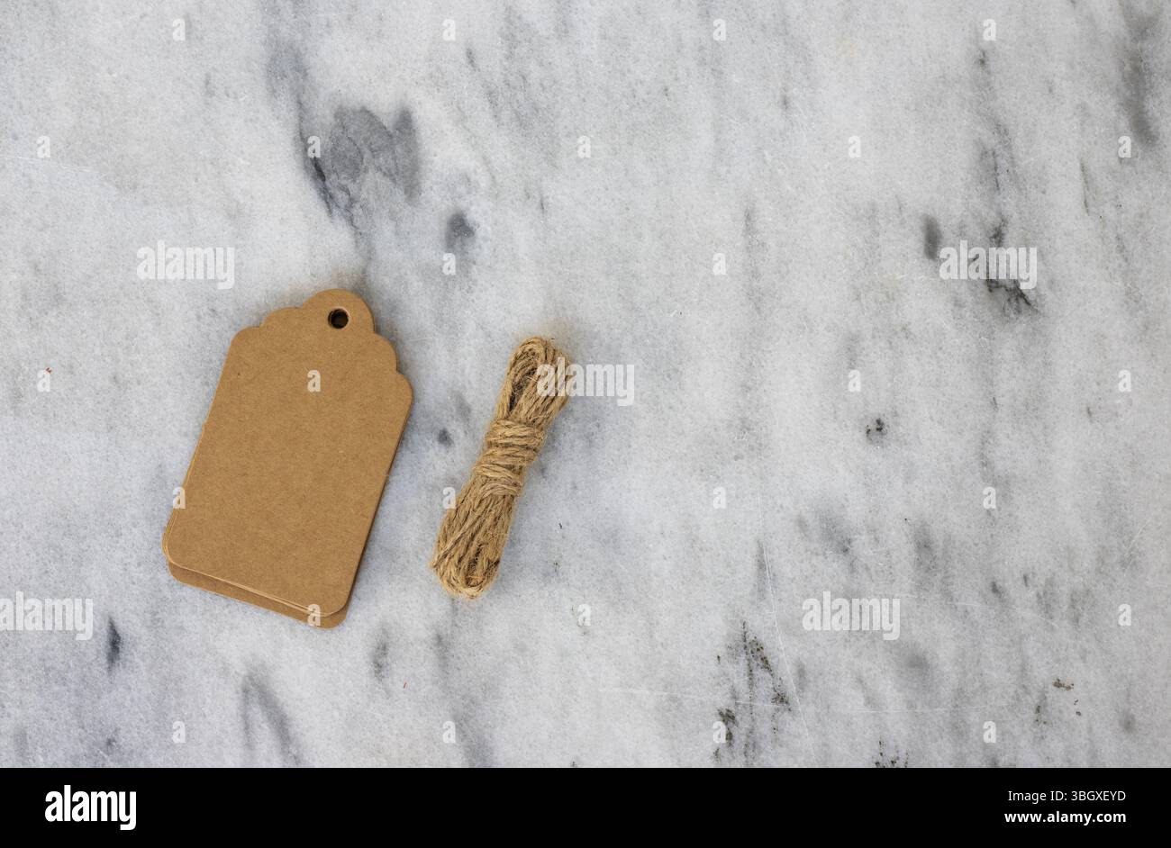 Stacked Kraft Gift Tags with Twine on Marble Background with Copy Space Stock Photo