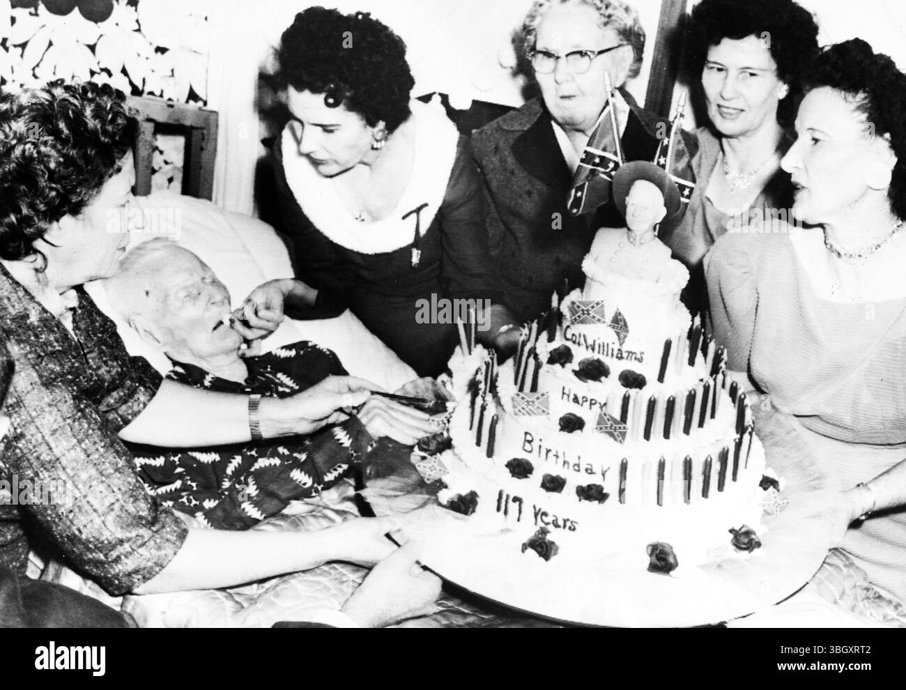 Walter William last surviving Civil War veteran celebrates his 117th birthday, with his five daughters presenting him with a giant cake.  Shown from left to right: Mrs Willie MAe Bowles, Williams, Mrs Beatrice Bielamowicz, Mrs Carrie James, Mrs Laura Childres and Mrs Lola Kintz.  15 November 1959. This Stock Photo