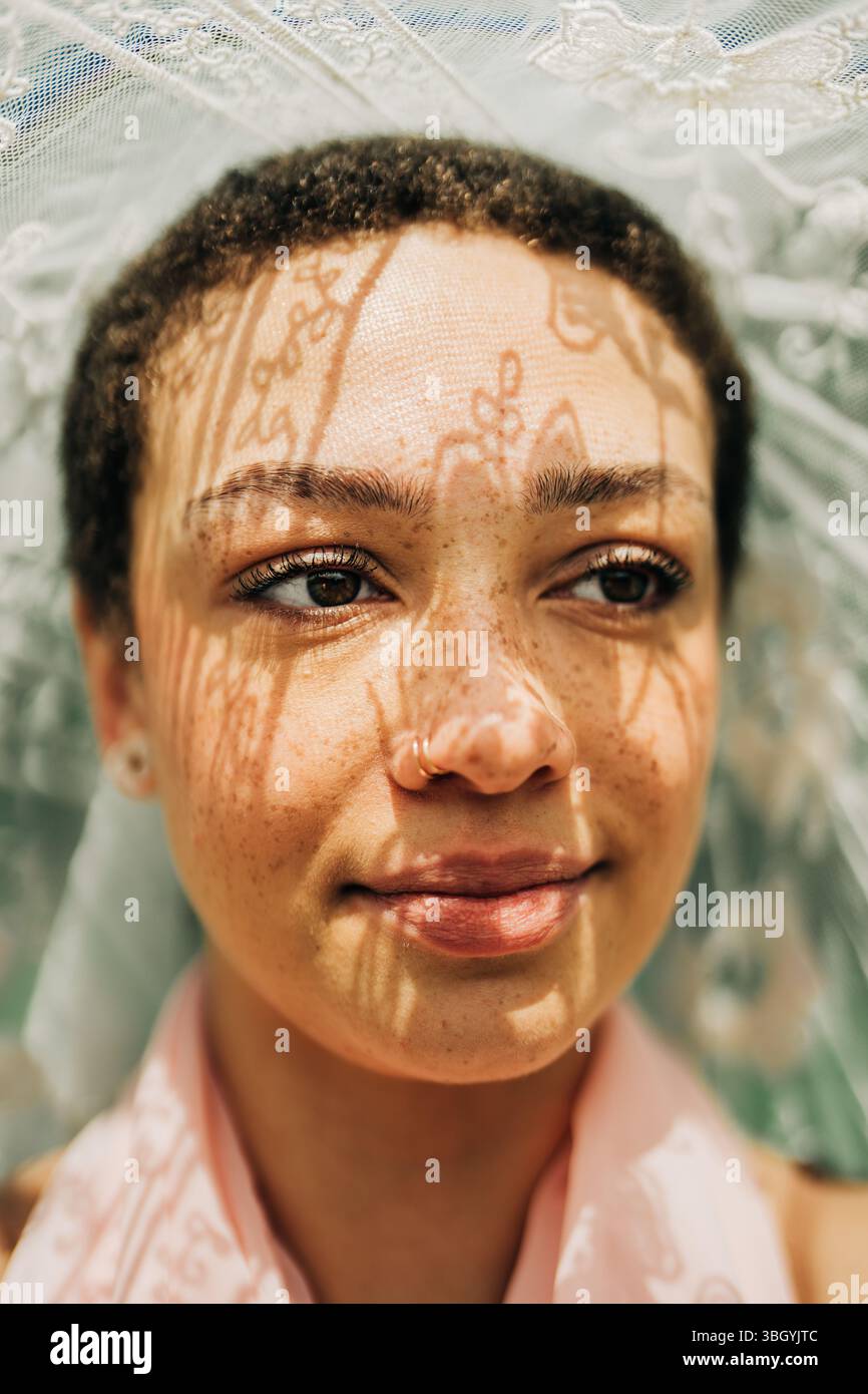 Woman smiling softly with lace shadow patterns on her face Stock Photo ...