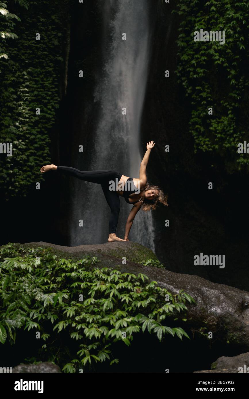 Woman balancing in yoga pose near jungle waterfall Stock Photo - Alamy