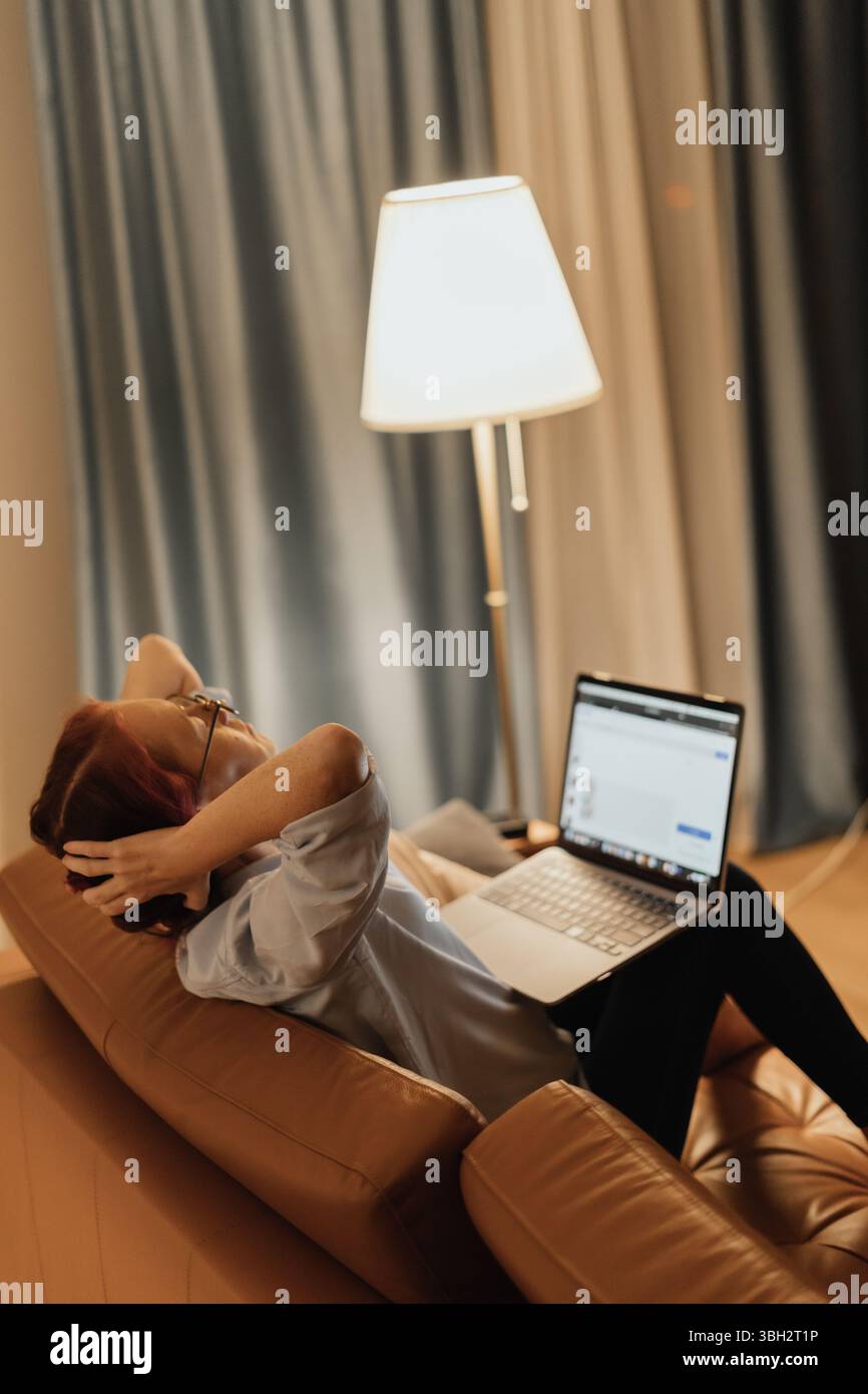 Woman suffers from tech neck and digital eye strain while working from home on laptop reflecting modern health issues caused by prolonged screen Stock Photo