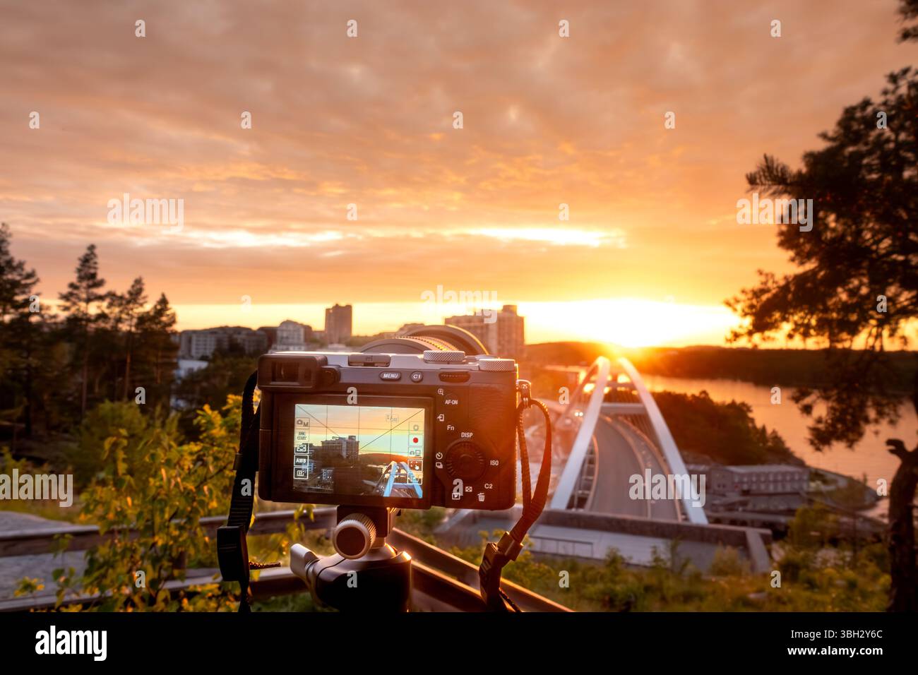 Professional photography with a camera on a tripod photographing an urban cityscape against the sun in sunset for a hobby concept Stock Photo