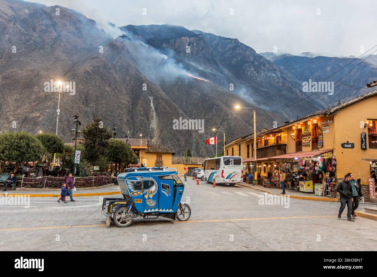 OLLANTAYTAMBO, PERU - NOVEMBER 7, 2022: Plaza de Armas square in Ollantaytambo village, Peru. Wildfire at the mountain in the background. Stock Photo