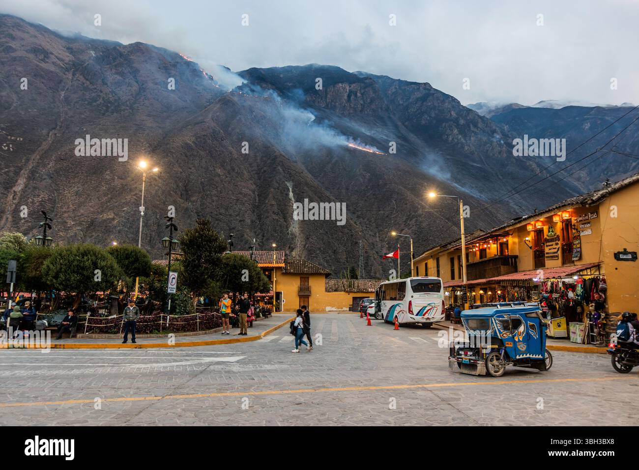 OLLANTAYTAMBO, PERU - NOVEMBER 7, 2022: Plaza de Armas square in Ollantaytambo village, Peru. Wildfire at the mountain in the background. Stock Photo