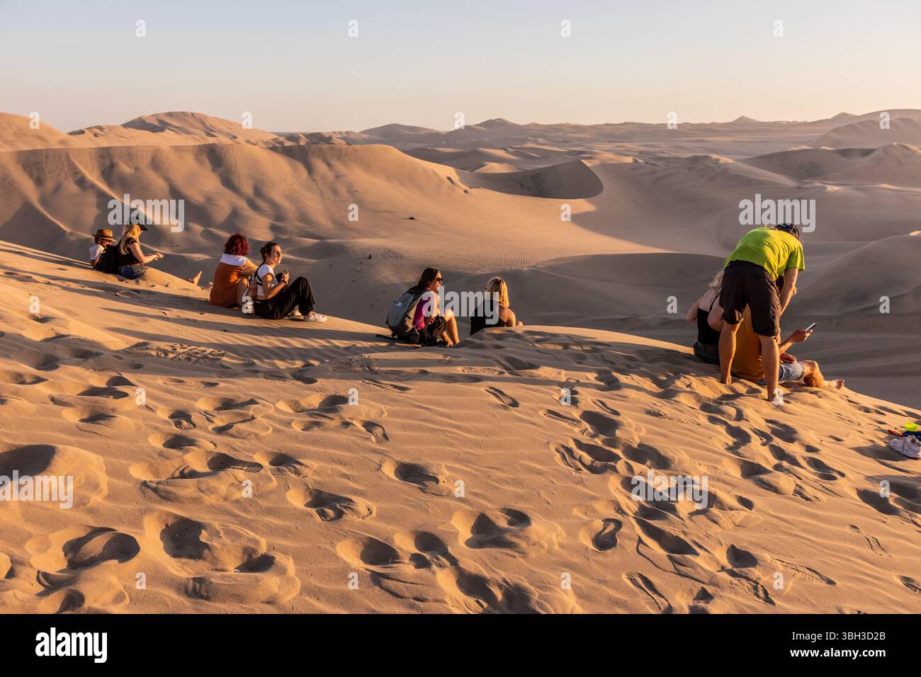 HUACACHINA, PERU - OCTOBER 27, 2022:  Tourists at a sand dune above Huacachina oasis near Ica town, Peru Stock Photo