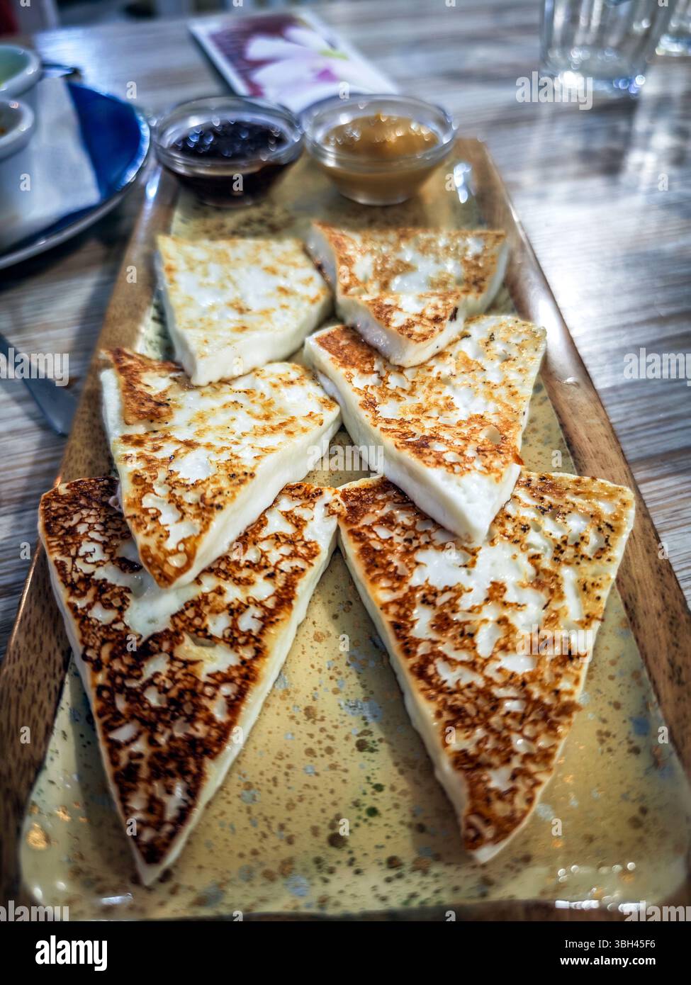 Delicious grilled goat cheese appetizer arranged on a plate with local sauces in Lanzarote, showcasing Canarian culinary traditions. Stock Photo