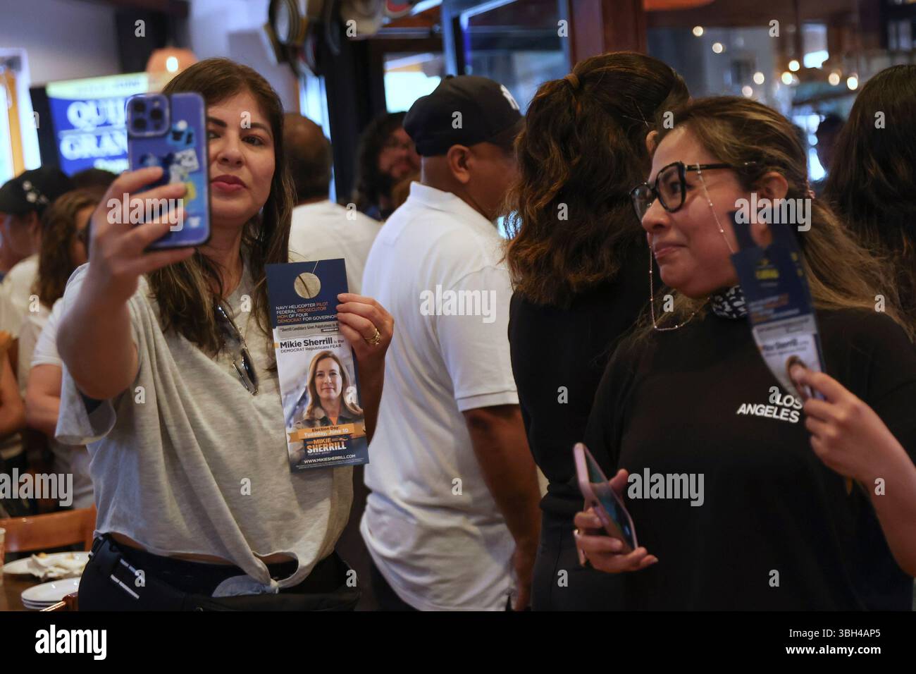 Attendees pose for photos holding a campaign pamphlet of Rep. Mikie ...