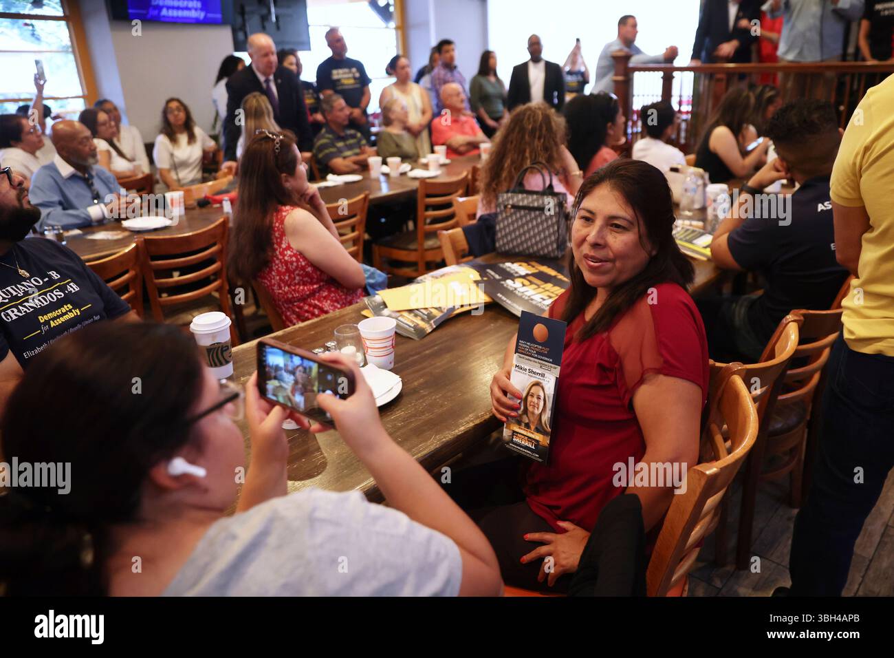 Attendees pose for photos holding a campaign pamphlet of Rep. Mikie ...