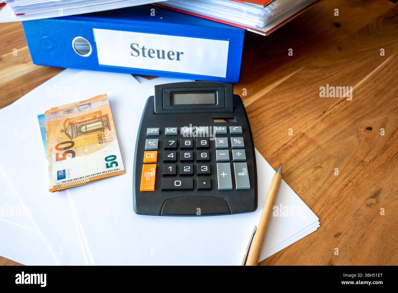 Blue, red, white folder with tax documents. Money euro bills, pen, calculator and paper on the table. Office steuer work for business. Stock Photo