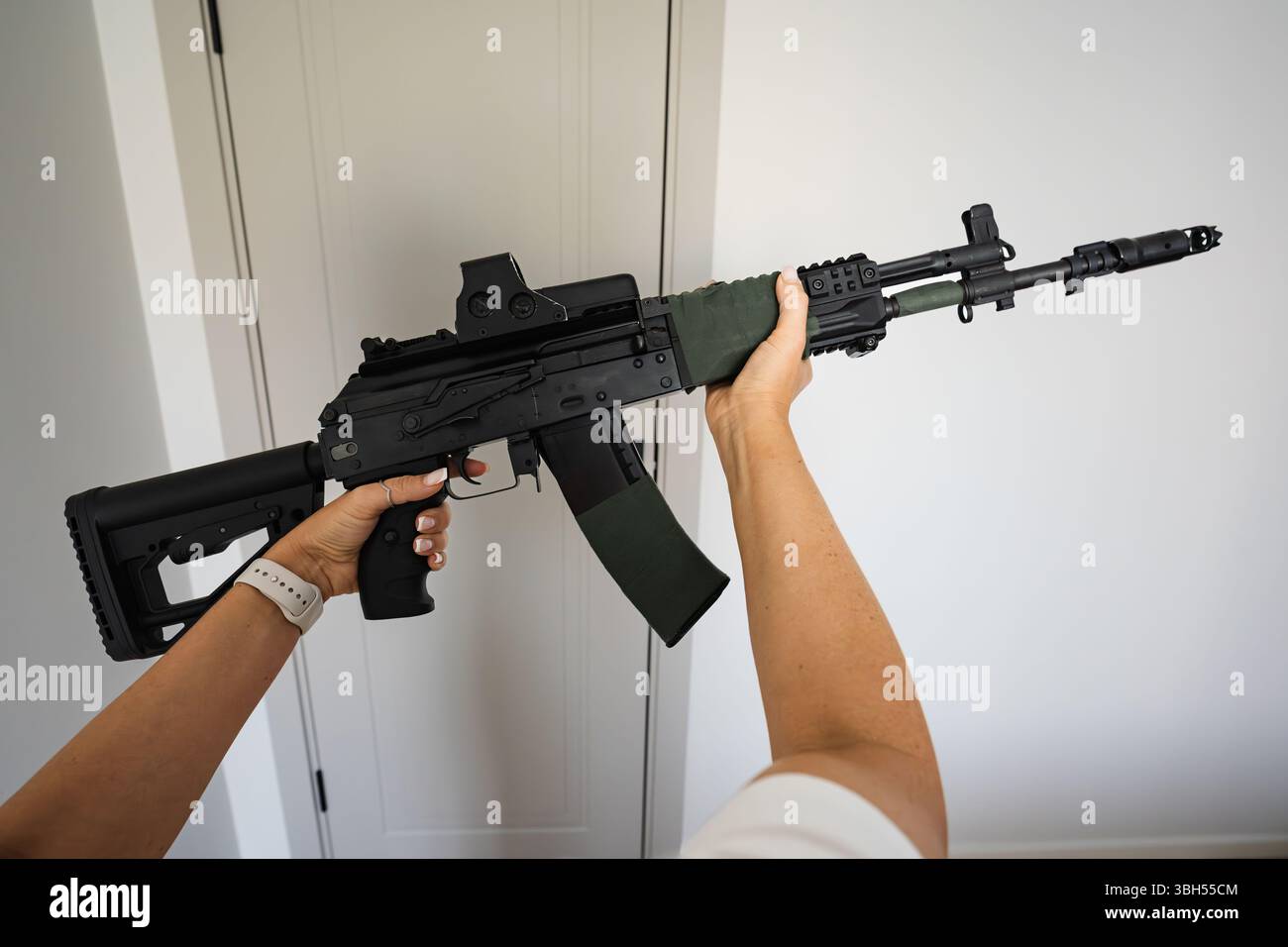 Tactical Security Rifle A woman holds a tactical assault rifle with a holographic sight, ready ...