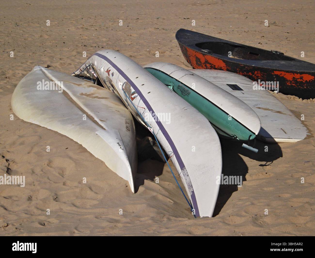 Kayaks and surfboards in the sand on a beach Stock Photo - Alamy