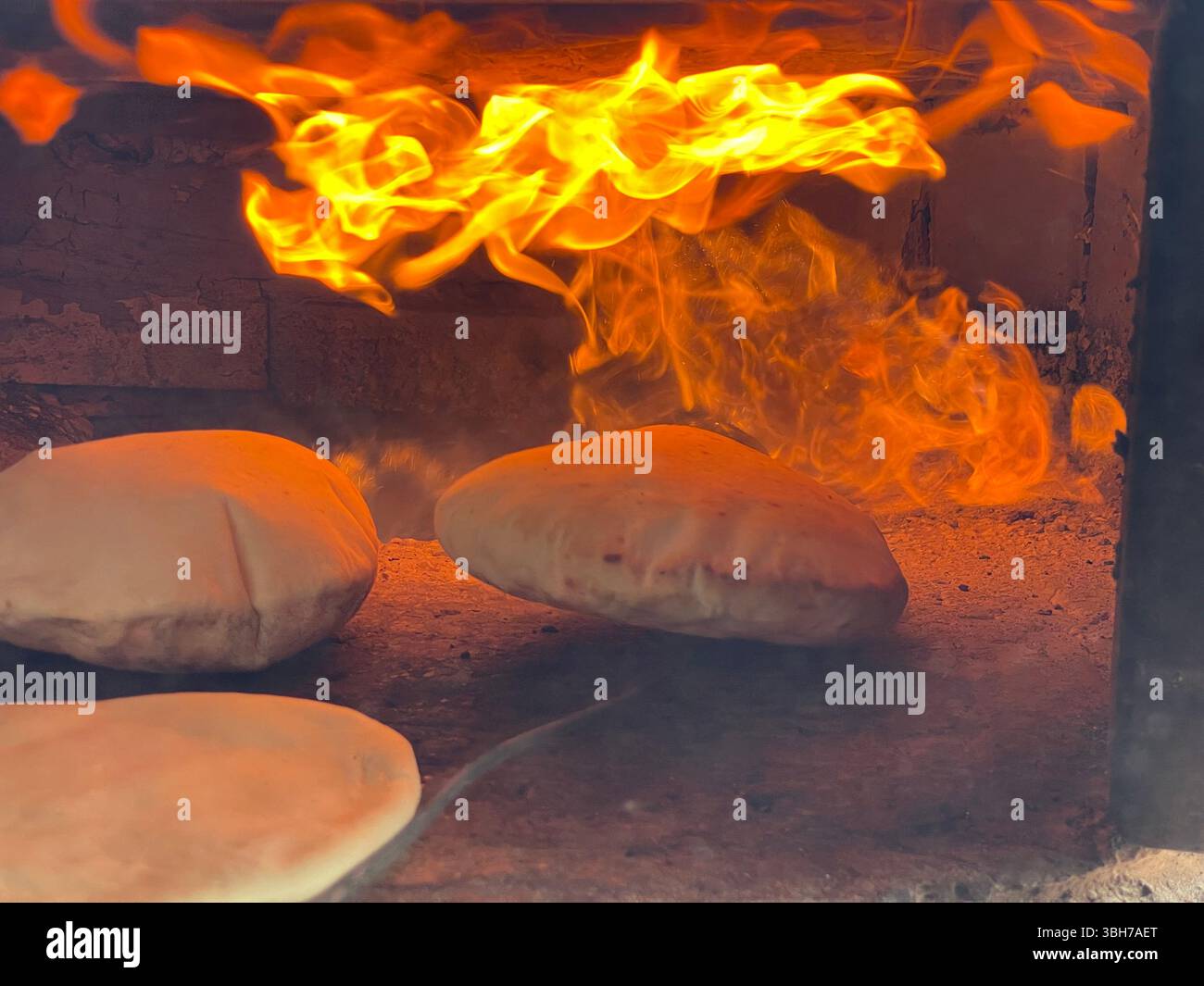 Traditional flatbread baking inside a clay oven Stock Photo