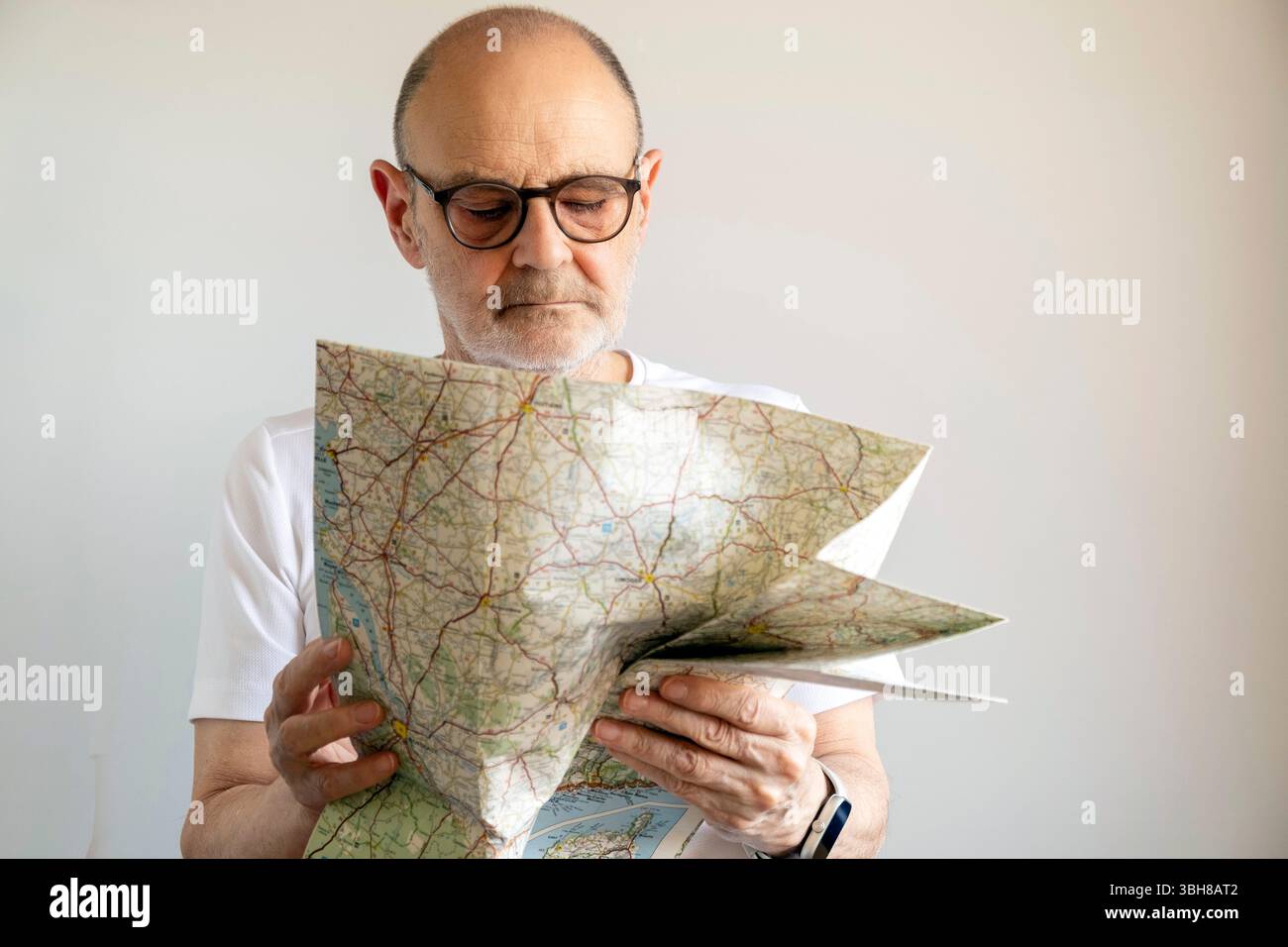 Navigate Man Elderly man intently examining a road map while standing indoors ...