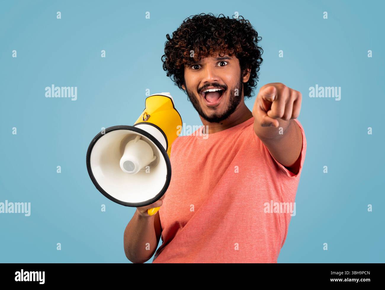 Handsome eastern guy shouting through loudspeaker and gesturing Stock Photo