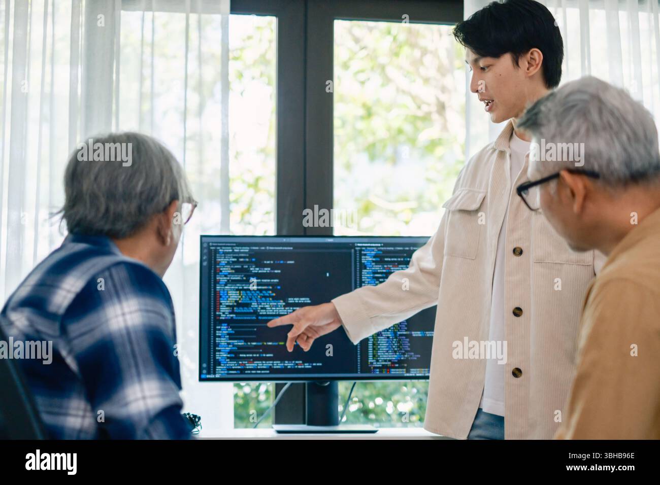 senior programmer bootcamlp,Asian young instructor guides senior learners through a programming on whiteboard, highlighting algorithm thinking and sim Stock Photo