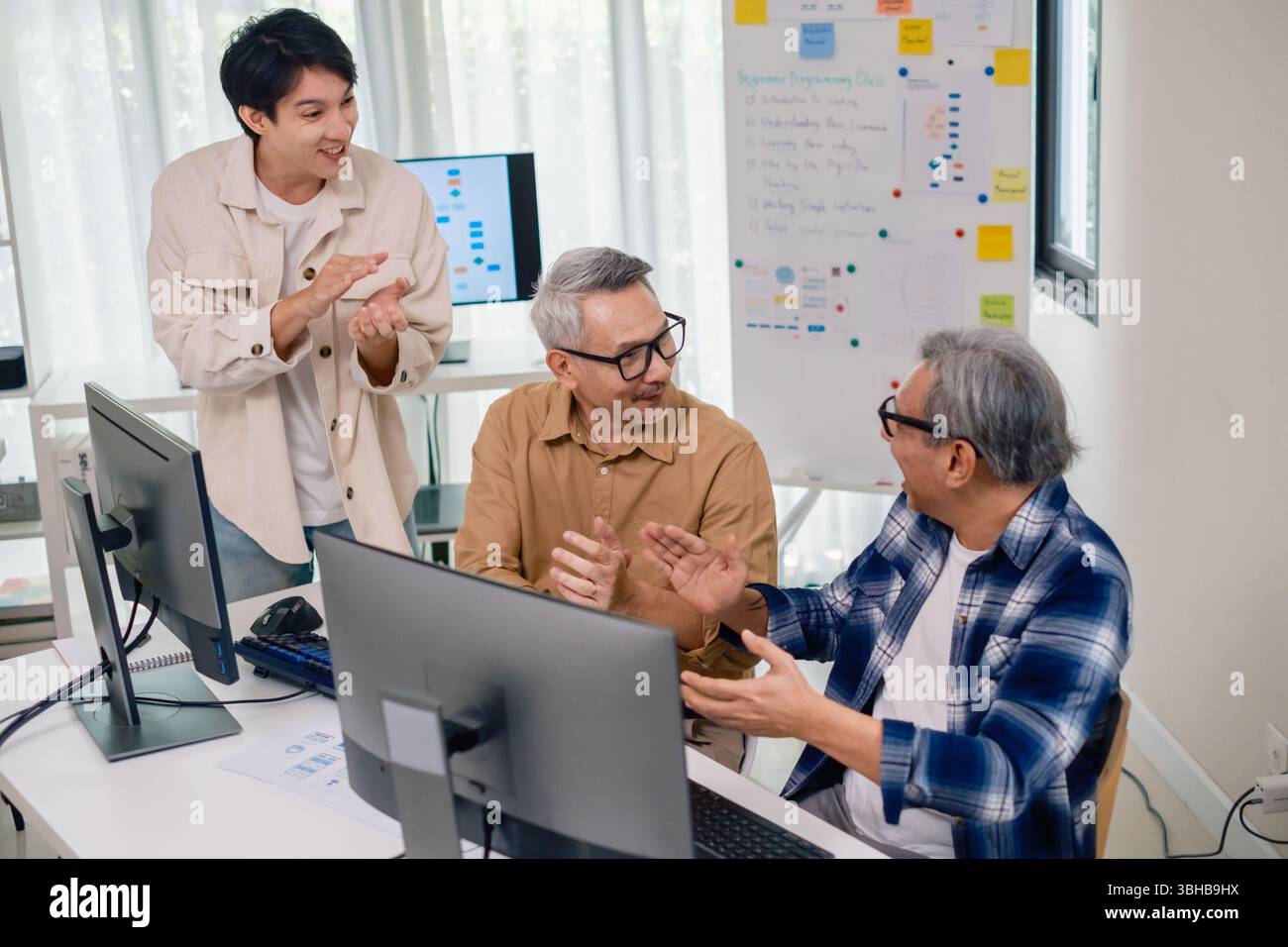 Senior developer team celebrates success in software collaboration and coding at a modern computer workstation Stock Photo