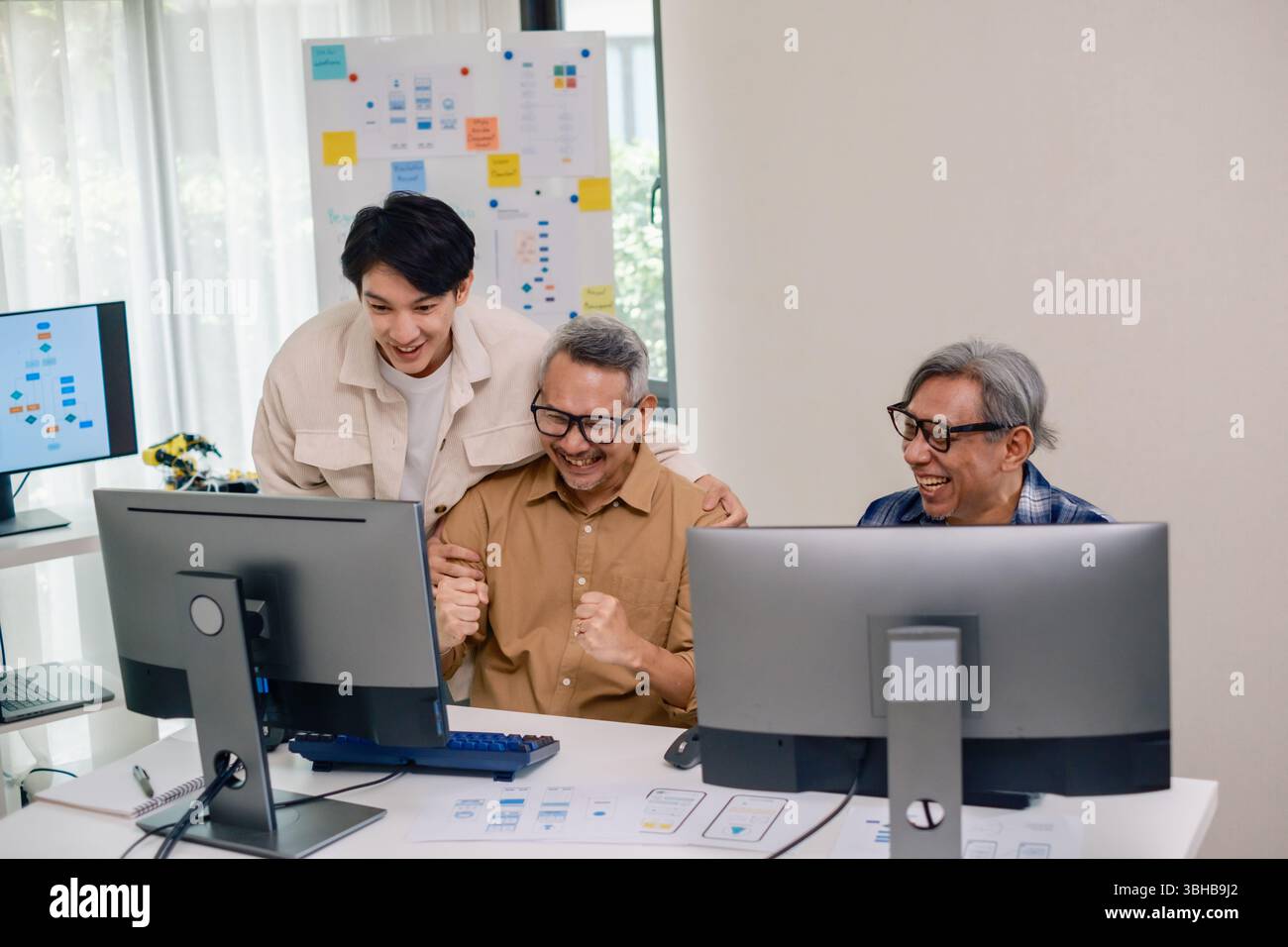 Senior developer team celebrates success in software collaboration and coding at a modern computer workstation Stock Photo
