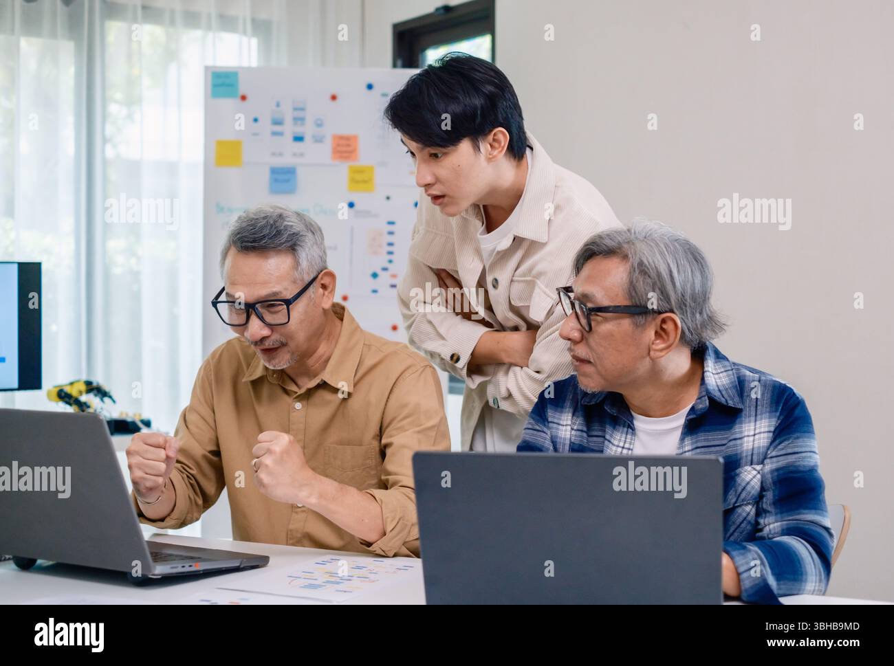 Senior developer team celebrates success in software collaboration and coding at a modern computer workstation Stock Photo